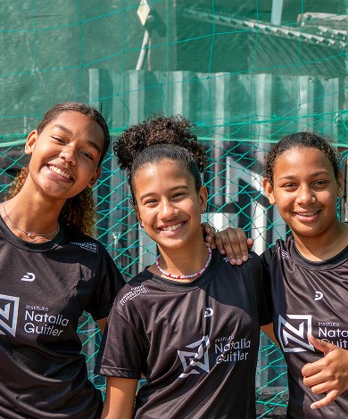 Três meninas sorrindo com uniformes do Instituto Natália Guitler