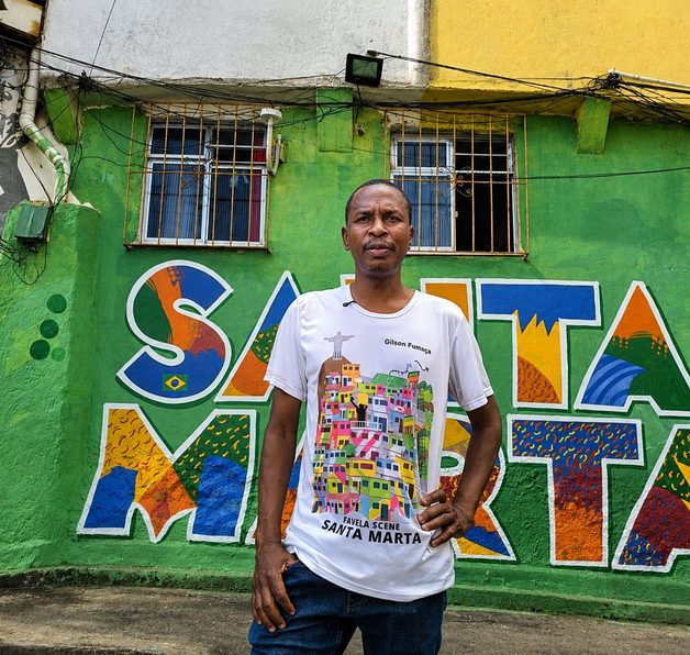 Morador de comunidade em frente a um mural colorido