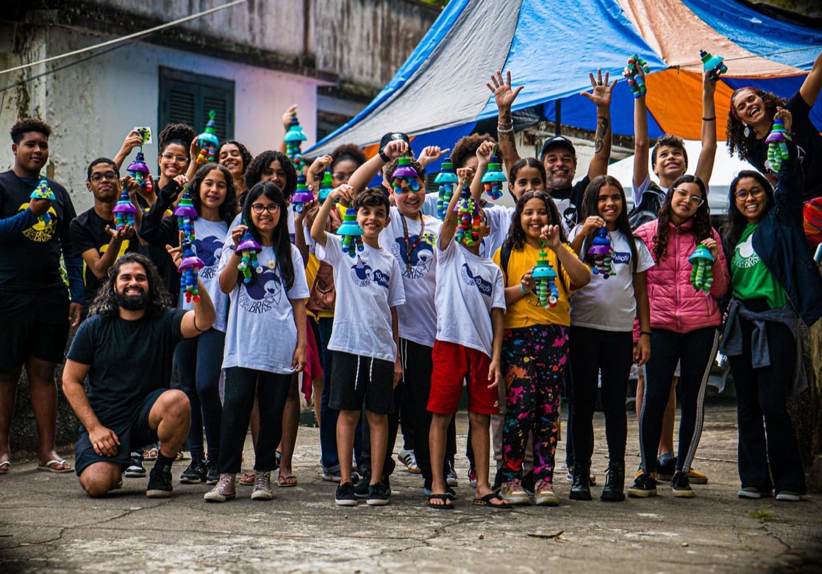 Crianças e jovens erguendo as luminárias que produziram na oficina